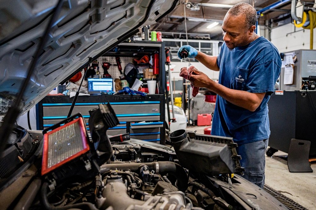 Mechanik kontroluje motor vozu, na dílenském vozíku běží diagnostika